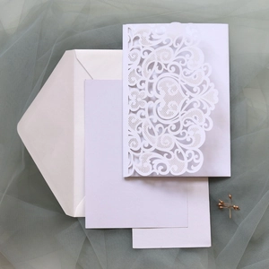 Intricate laser-cut wedding invitation set with delicate scroll patterns and envelopes