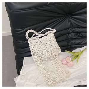 Detailed macro view of bohemian hand-woven cotton shoulder bag with long fringe tassels
