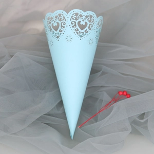 Detail of light blue laser-cut paper cone with heart pattern for wedding petals