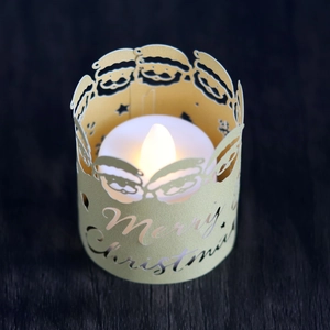 Close-up of golden laser-cut Merry Christmas candle cover with Santa Claus and LED light