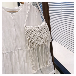 Detailed close-up of bohemian white cotton woven bag with wheat ear texture and tassels