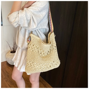 Détail d'un sac cabas en paille tissée beige avec bandoulière colorée aux motifs ethniques