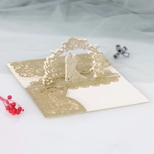 Macro detail of laser-cut 3D wedding invitation with gold glitter and floral arch