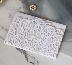 Macro shot of laser-cut white pearl paper wedding invitation with intricate lace patterns