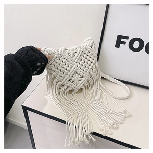 Detail of white handmade woven crossbody bag with bohemian tassel and diamond pattern