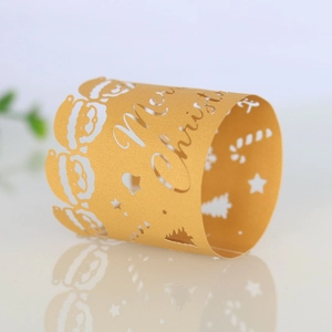Close-up of golden laser-cut Merry Christmas paper napkin ring with reindeer and tree