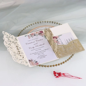 Detail of laser-cut wedding invitation with cream hollow lace and gold glitter accents