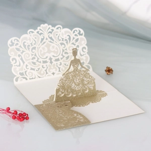 Detail of 3D pop-up invitation featuring a laser-cut gold glitter dress and scroll patterns
