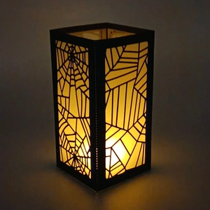 Close-up of Halloween lantern featuring a spider web laser-cut design with warm light