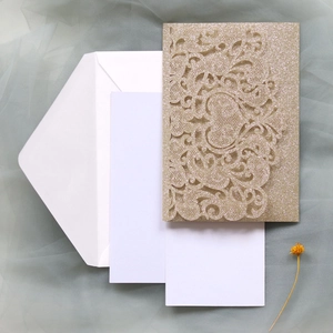 Laser cut champagne gold wedding invitation set with envelopes on soft fabric background
