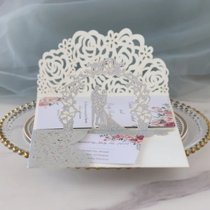 Détail d'invitation de mariage découpée au laser avec rose 3D et couple à paillettes