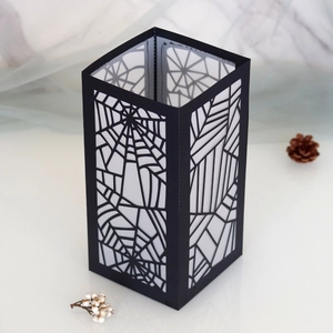 Macro detail of laser-cut spider web pattern on black Halloween paper lampshade