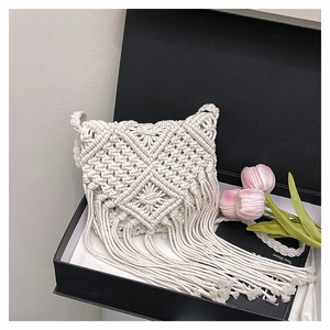 Detail of handmade bohemian woven cotton crossbody bag with long tassels in a gift box