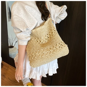 Détail du motif floral tissé sur un sac à main en paille beige de style bohème