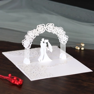 Macro view of laser-cut 3D wedding invitation showing a couple kissing under a rose arch