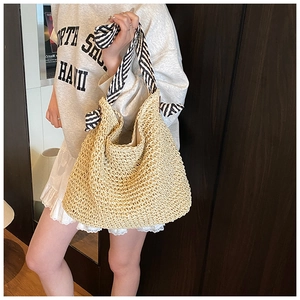 Détail d'un sac cabas en paille tissé avec poignées nouées à rayures noires et blanches