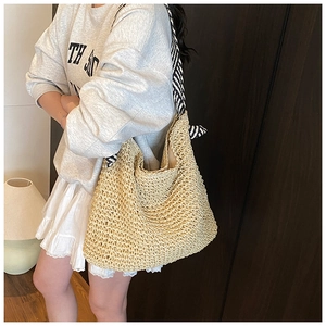 Détail du sac cabas en paille tressée avec d'élégantes bandoulières en tissu rayé noir et blanc