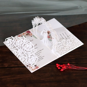 Detail of laser-cut wedding invitation featuring intricate rose patterns and 3D silhouette