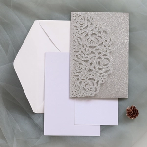 Macro detail of laser-cut rose glitter paper wedding invitation with white insert cards