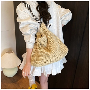 Détail d'un sac cabas tissé beige avec une bandoulière en foulard rayé noir et blanc