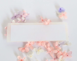 Macro detail of white blank wedding card surrounded by pastel pink and purple dried flowers