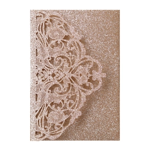 Macro shot of laser-cut floral pattern on rose gold glitter cardstock wedding invitation