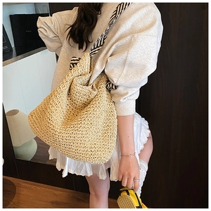 Gros plan d'un sac cabas en paille tressée avec une bandoulière en tissu rayé noir et blanc