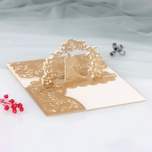 Detailed laser-cut gold glitter wedding invitation featuring a 3D pop-up couple and arch