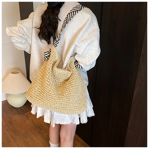 Détail du sac hobo en paille tressée avec bandoulière rayée noire et blanche élégante