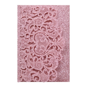Close-up of pink glitter laser-cut lace wedding invitation with intricate floral details