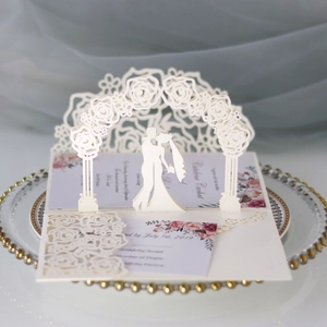 Detail of 3D laser-cut wedding invitation featuring rose arch and kissing couple