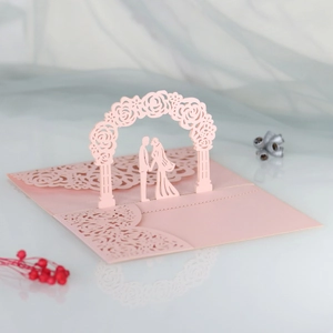 Pink laser-cut pop-up wedding invitation featuring a romantic 3D rose arch and couple detail