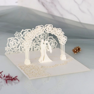 Close-up of 3D laser-cut wedding card with couple under a rose arch detail