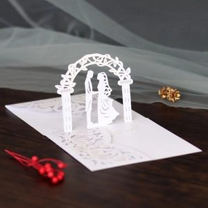 Detail of laser-cut 3D white wedding invitation featuring a romantic couple under an arch