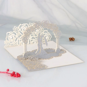 Macro detail of laser cut 3D pop-up wedding card with glittery silver rose arch and couple