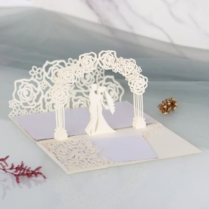 Detail of 3D laser-cut wedding invitation featuring a romantic couple and rose arch