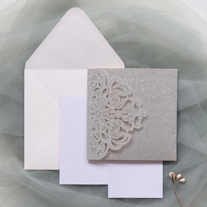 Details von silberner Glitzer-Hochzeitseinladung mit Laserschnitt-Spitzenmuster und Umschlag