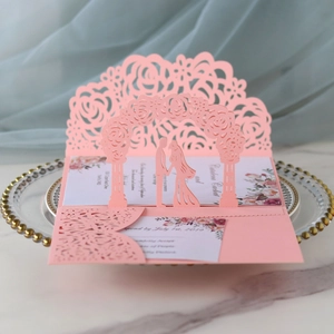 Detail of pink laser-cut 3D pop-up wedding invitation with rose arch and couple silhouette