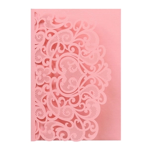 Close-up of pink laser-cut invitation card with intricate floral and heart patterns