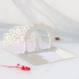 Close-up of 3D laser cut silver glitter wedding card with kissing couple and roses