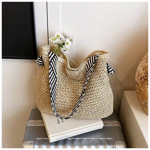 Détail du sac cabas en paille tissée avec des anses en tissu rayé noir et blanc
