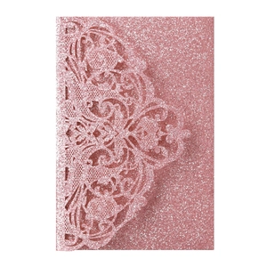 Close-up of laser-cut rose gold glitter wedding invitation with intricate lace detailing