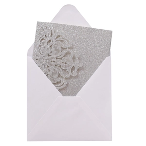 Makroaufnahme der silbernen Glitzer-Einladung mit lasergeschnittener Spitze und Blumen