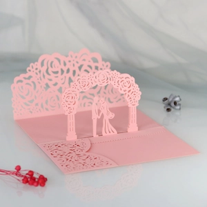 Detail of 3D laser-cut wedding card featuring a pink rose lace gate and couple silhouette