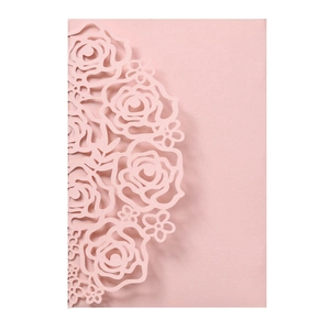 Detail showing the intricate laser-cut rose design on a light pink wedding invitation card