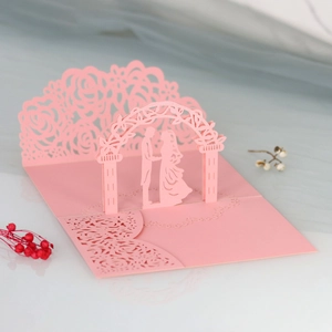 Dettaglio dell'invito di nozze 3D rosa con silhouette degli sposi tagliata al laser