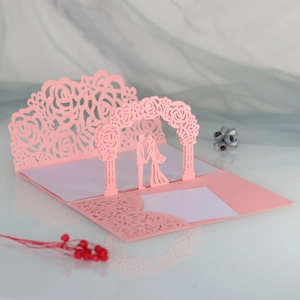 Macro detail of pink laser-cut 3D wedding invitation with rose hollow patterns and couple silhouette