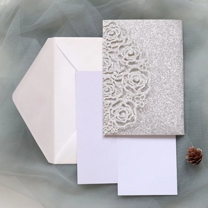 Macro detail of laser-cut rose hollow invitation with silver glitter finish and envelope