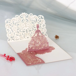 Macro shot of 3D laser-cut wedding invitation featuring a pink glitter princess dress