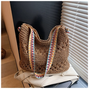 Détail du sac fourre-tout en paille tissé main avec motifs floraux et bandoulière tissée colorée